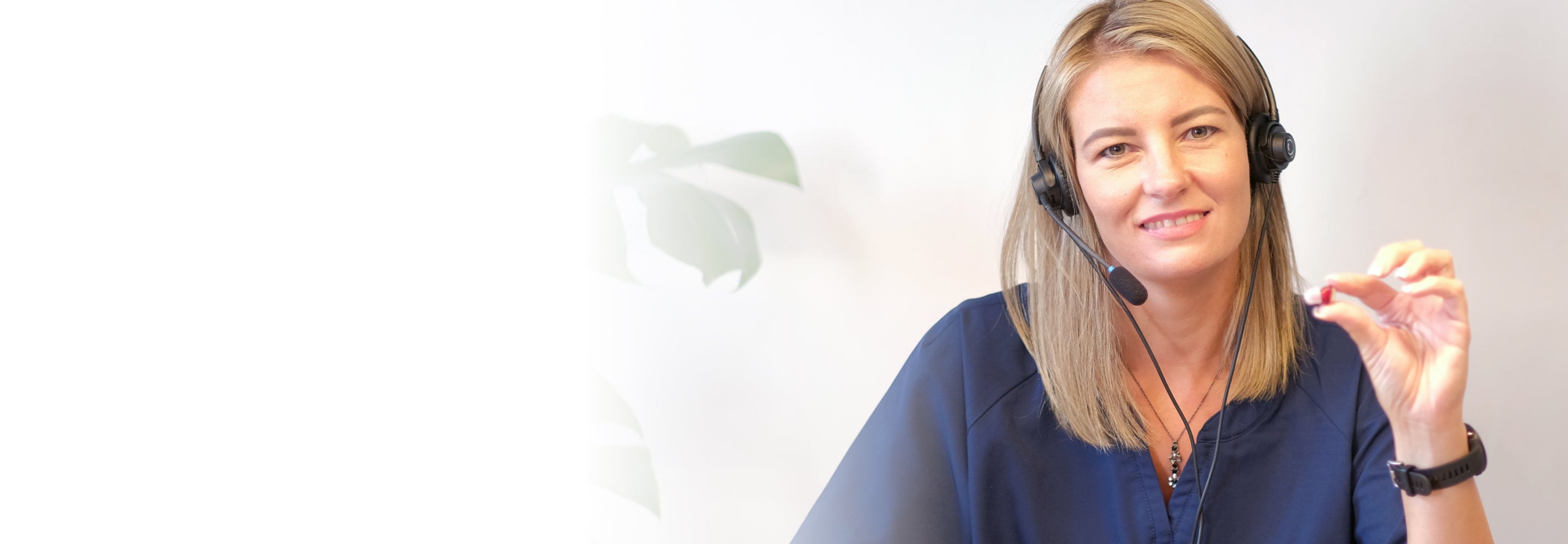 Smiling Go hearing aid product expert, wearing a headset and holding one in-the-ear Go hearing aid.