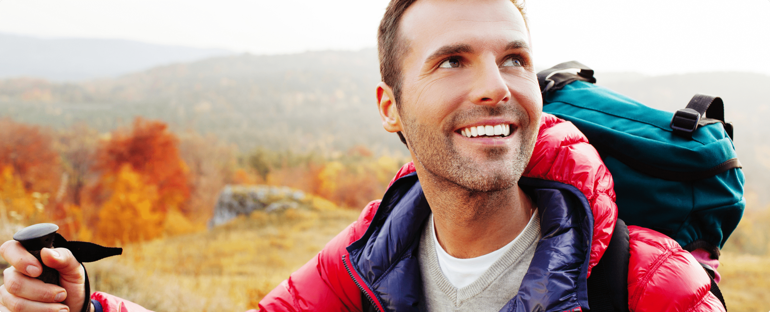 Middle-aged man hiking in the mountains wearing Go over the counter hearing aids.
